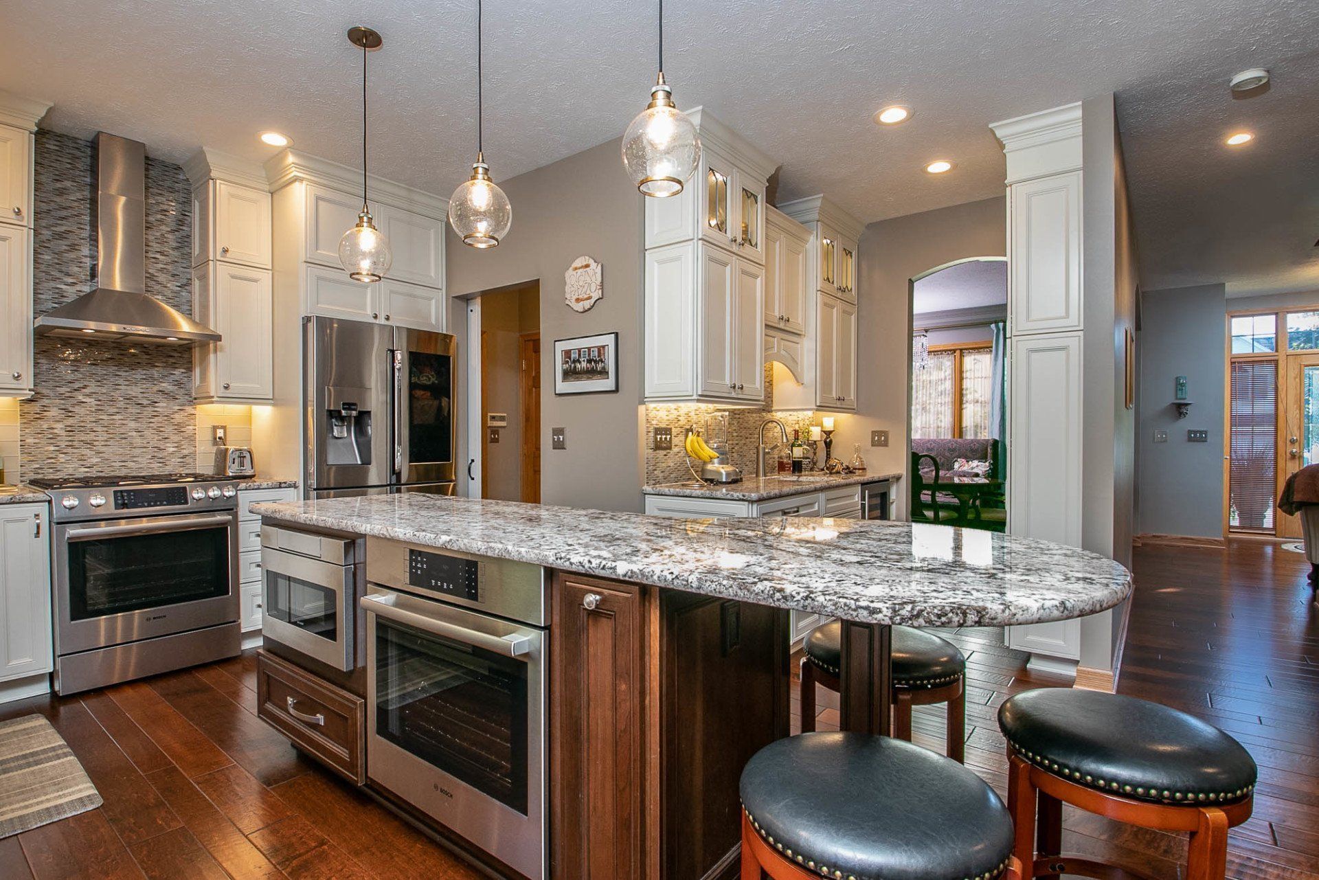 A kitchen with granite counter tops , stainless steel appliances , and white cabinets.