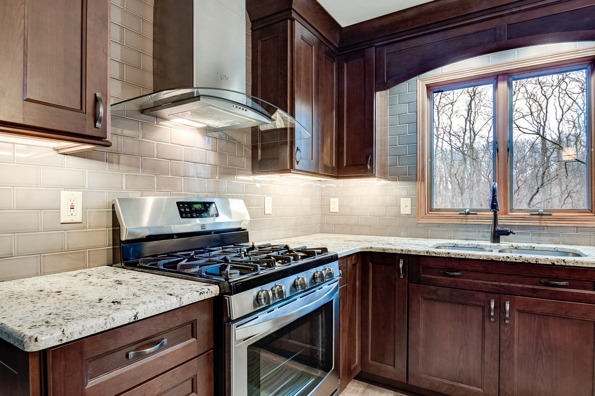 A kitchen with stainless steel appliances , granite counter tops , and wooden cabinets.