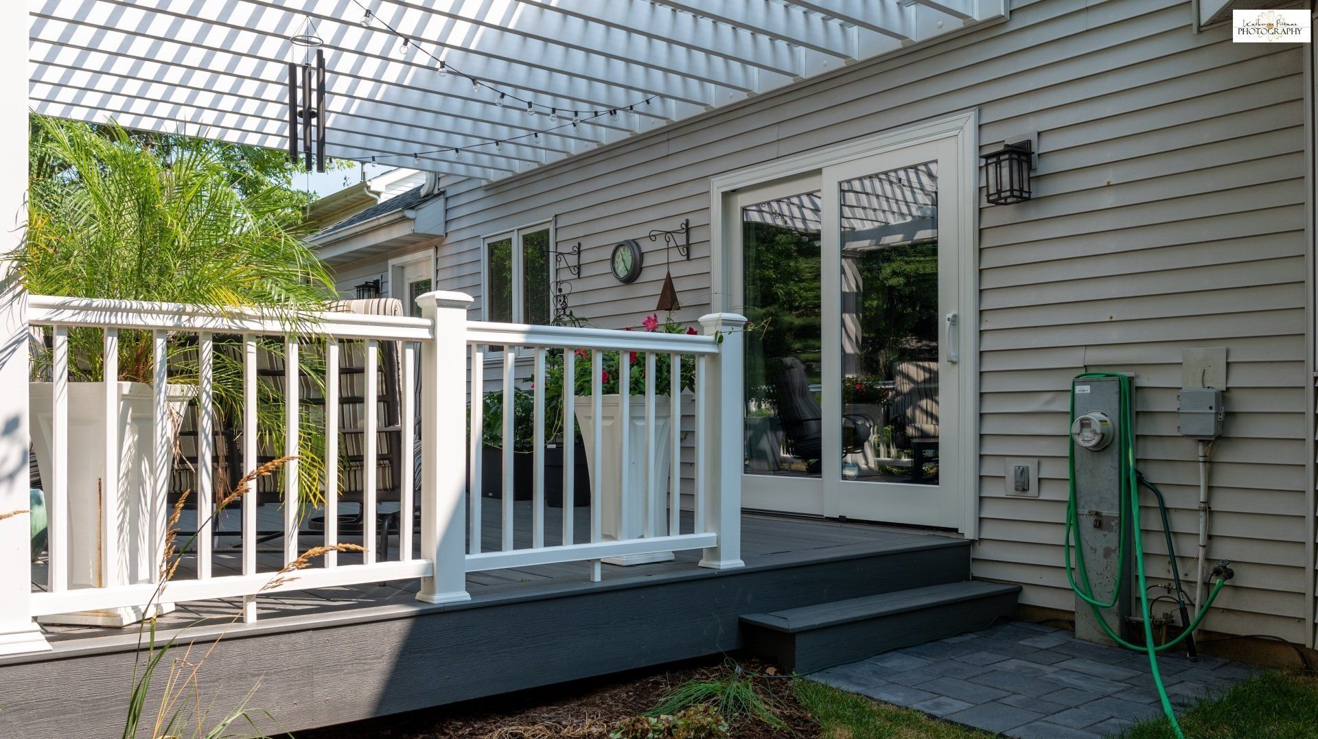 A deck with a white railing and sliding glass doors