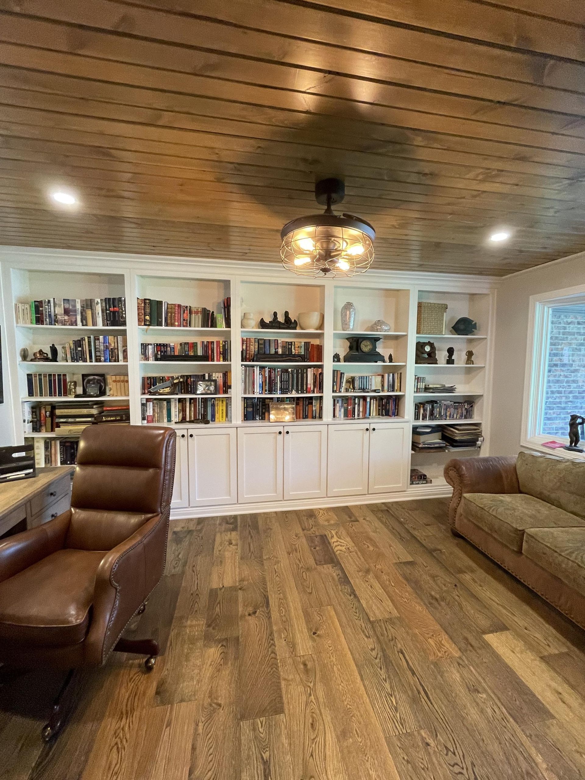 A living room with a couch , chair , desk and bookshelves.