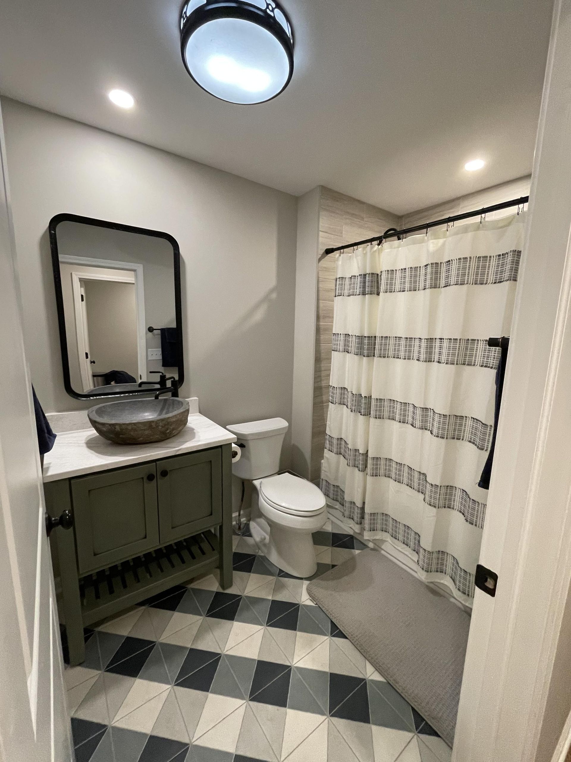 A bathroom with a toilet , sink , mirror and shower curtain.