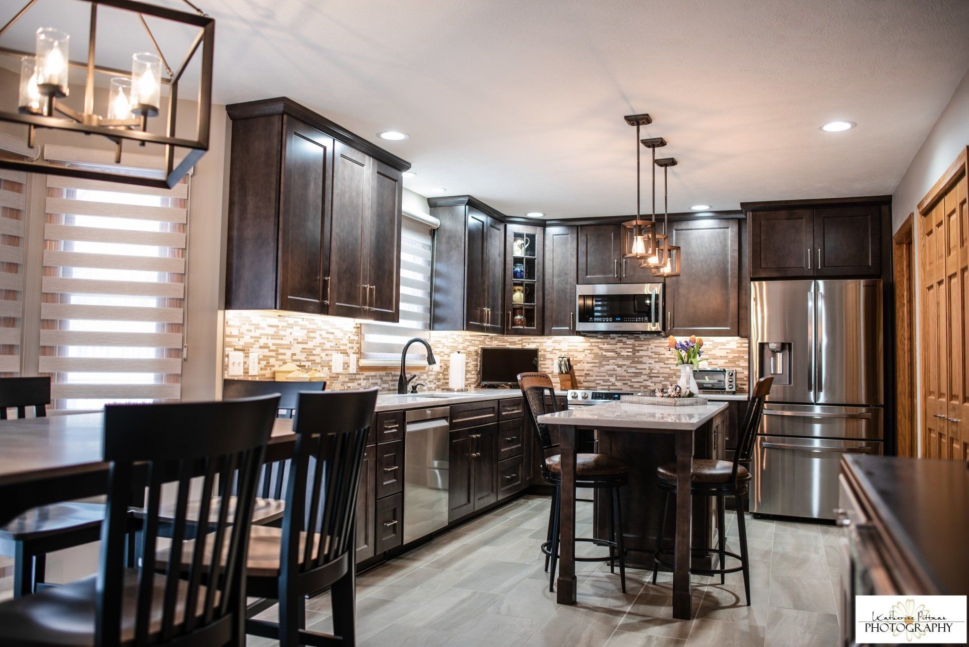 A kitchen with stainless steel appliances , wooden cabinets , a table and chairs.