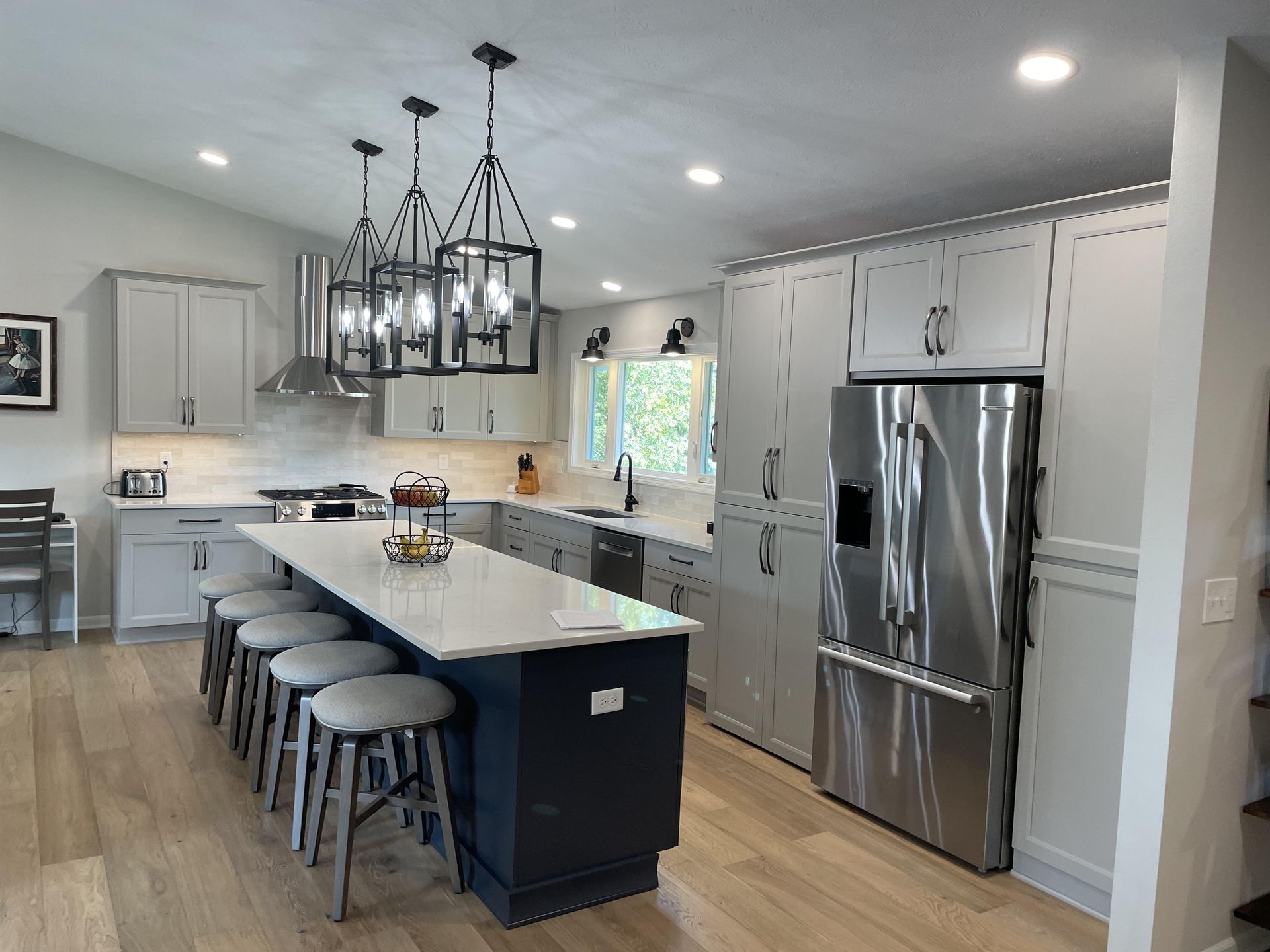 A kitchen with white cabinets , stainless steel appliances and a large island.