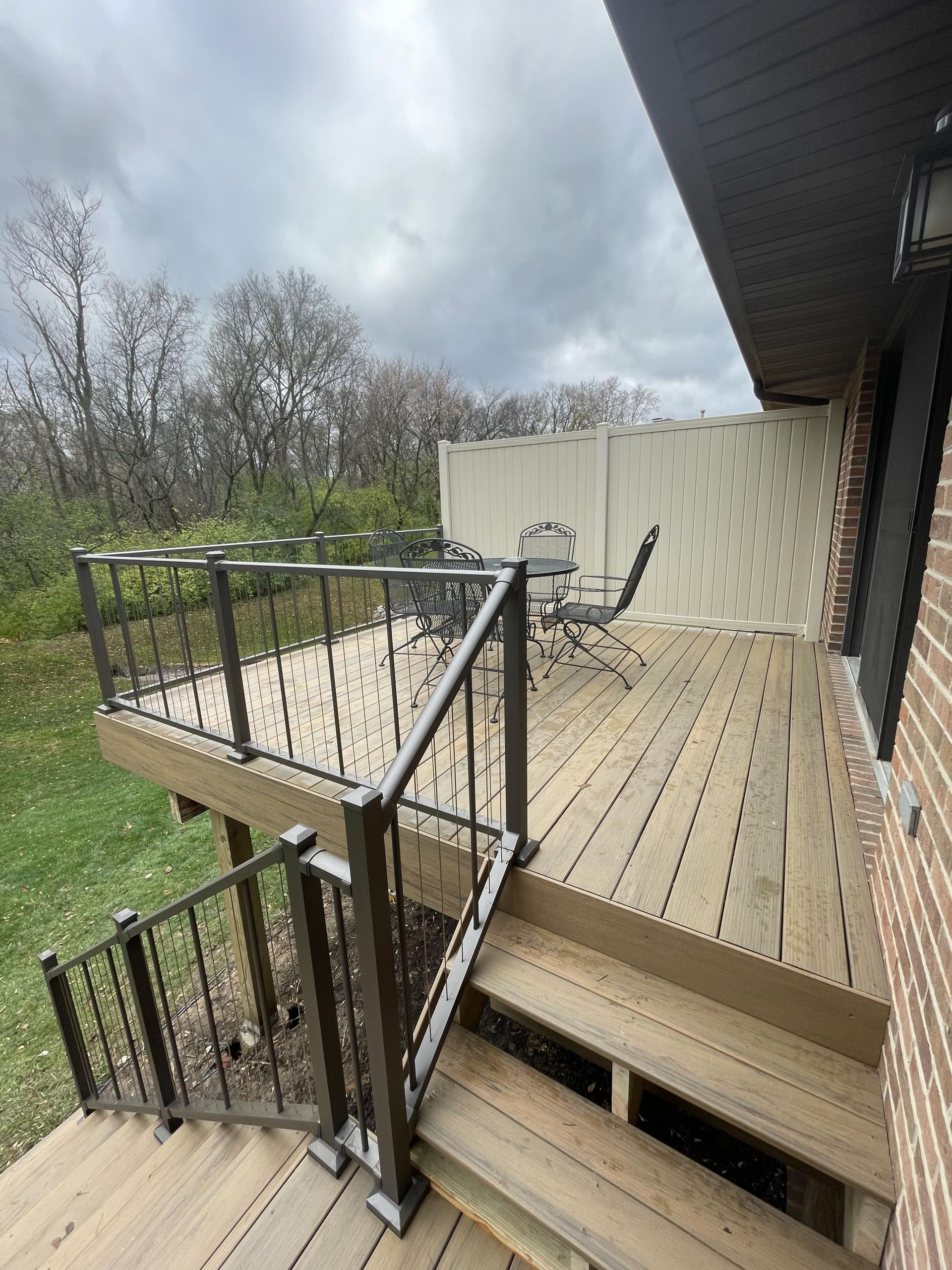 A wooden deck with stairs leading up to it and a table and chairs on it.