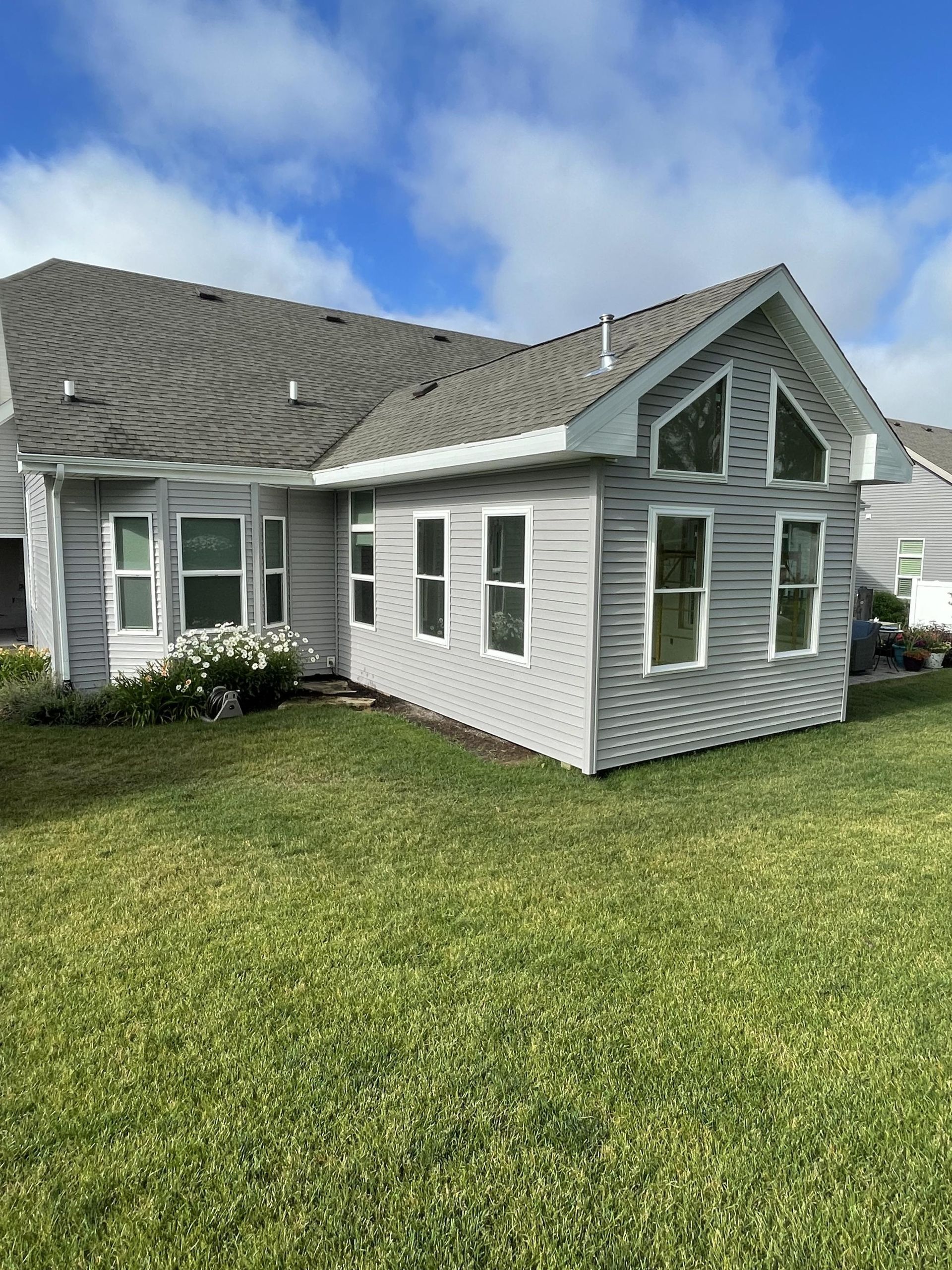 A house with a lot of windows is sitting on top of a lush green lawn.