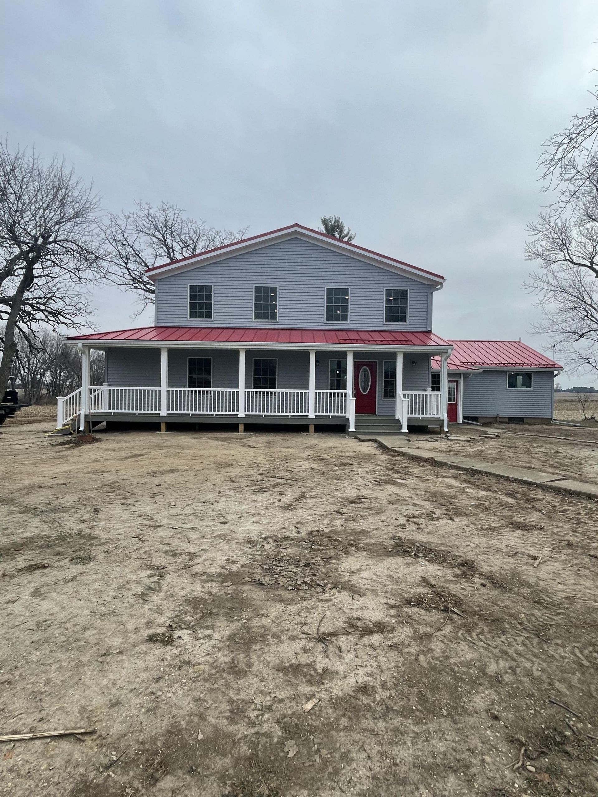 A large white house with a red roof and a large porch.