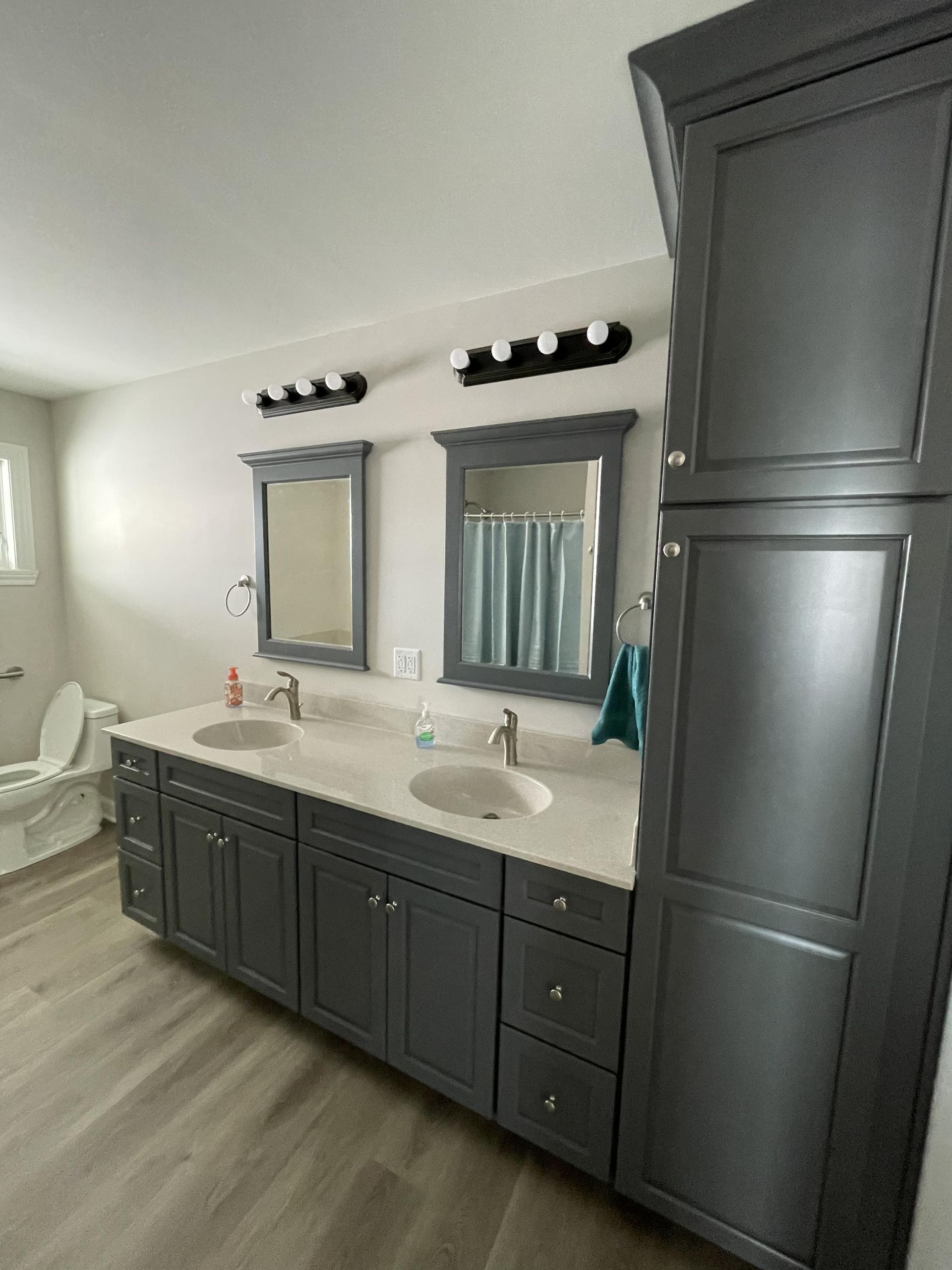 A bathroom with two sinks , two mirrors and a toilet.