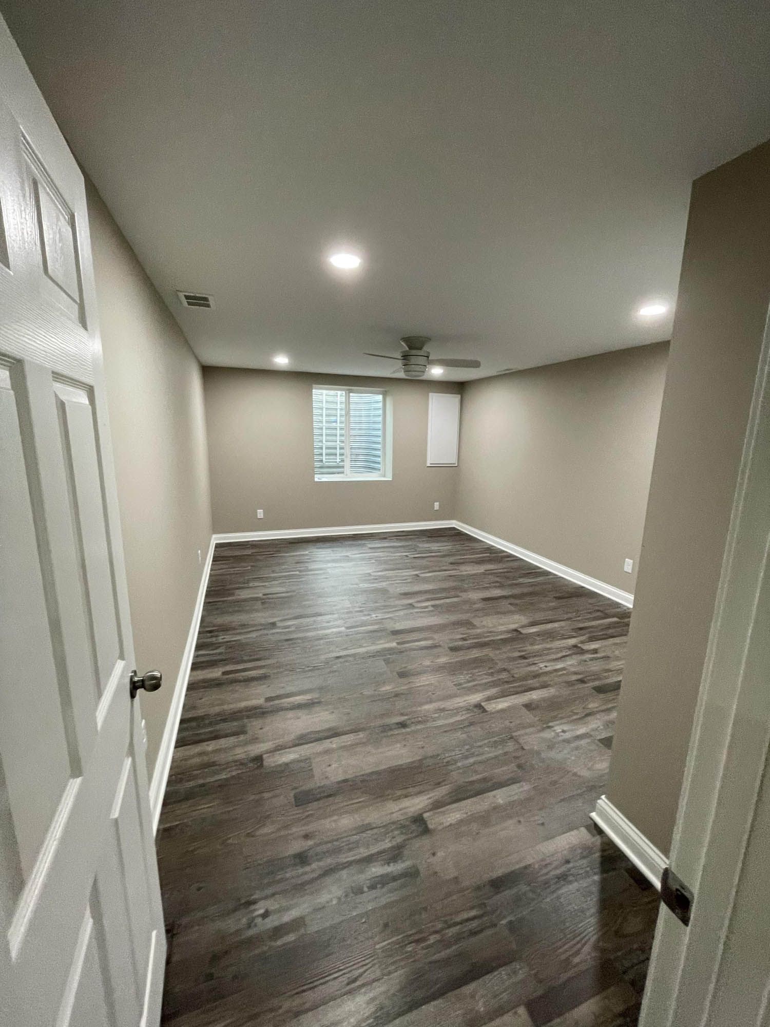 A large empty room with hardwood floors and a window.
