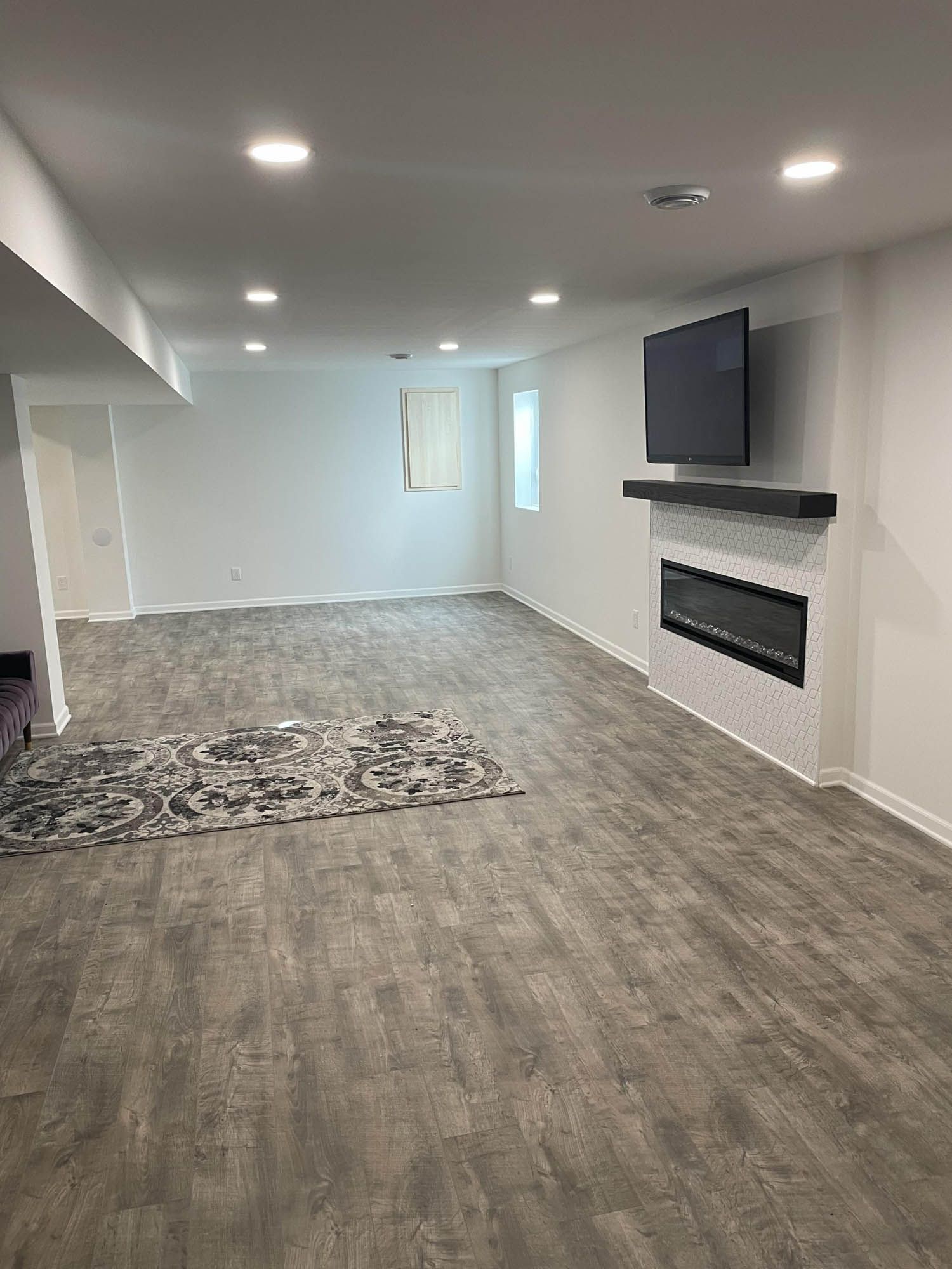 A large empty basement with a fireplace and a flat screen tv.
