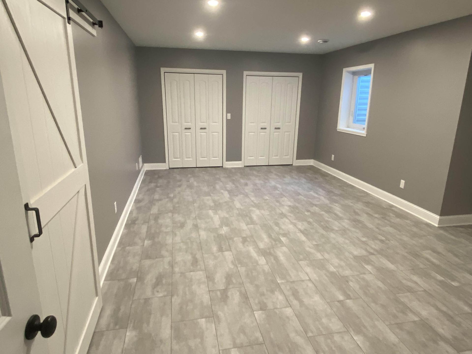 A large empty room with gray tile floors and gray walls.