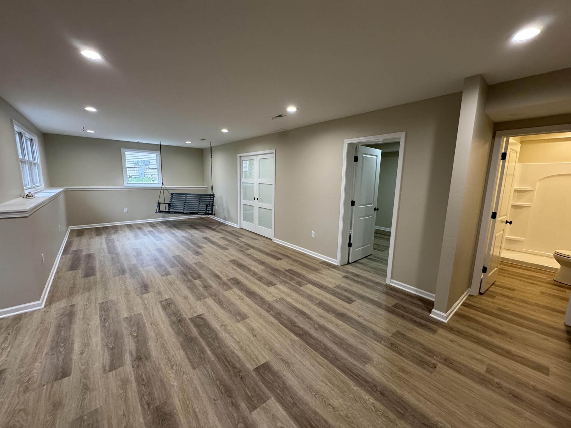 A large empty room with hardwood floors and a bathroom.