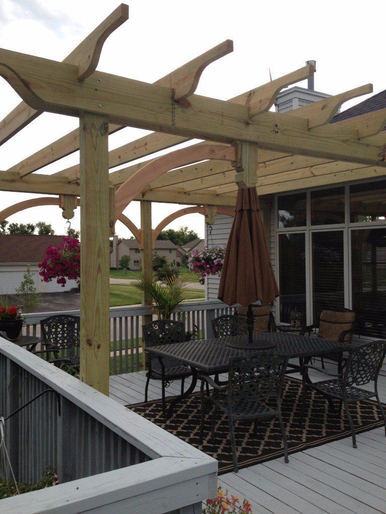 A deck with a table and chairs under a pergola