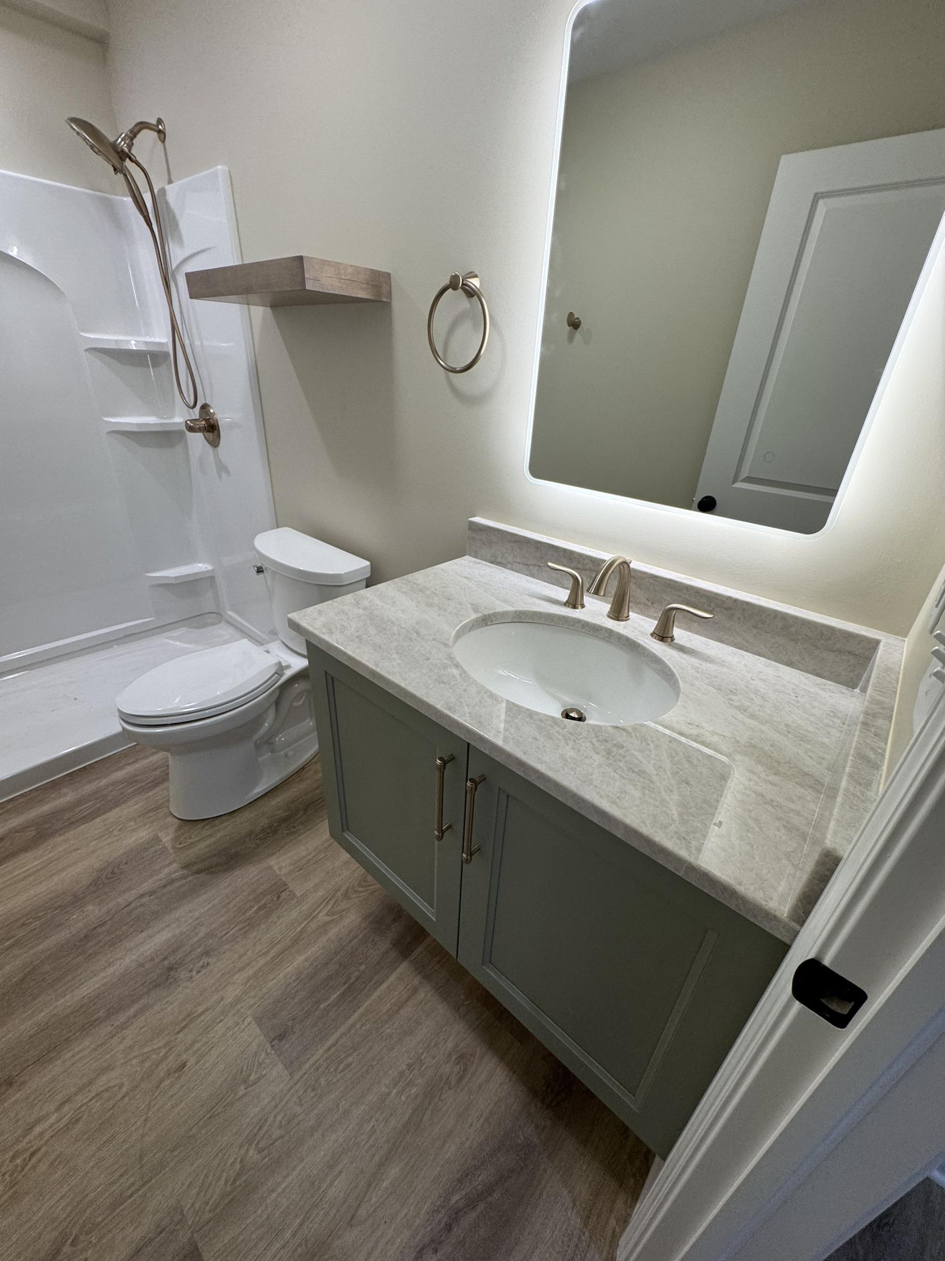 A bathroom with a sink , toilet , shower and mirror.
