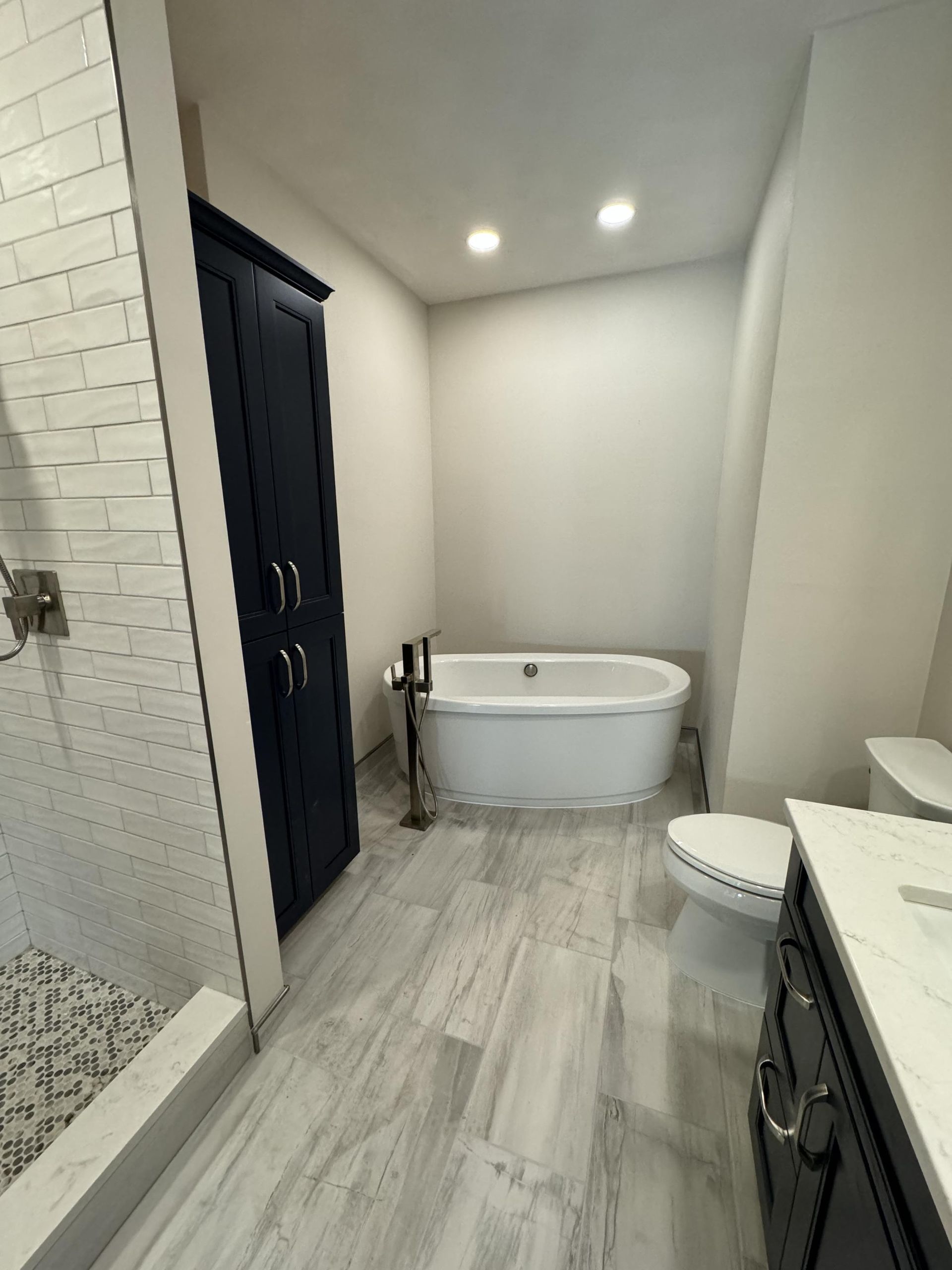 A bathroom with a tub , toilet , sink and shower.