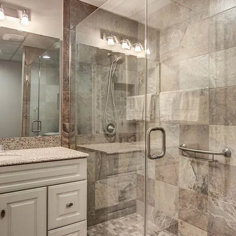 A bathroom with a walk in shower , sink and mirror.