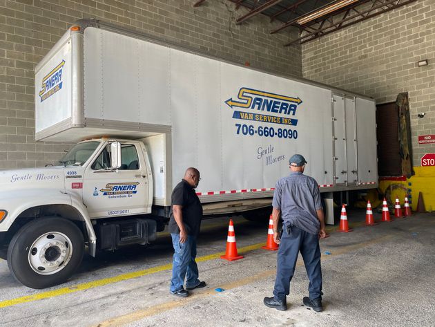 White delivery trucks parked in a row against a blue sky with clouds.