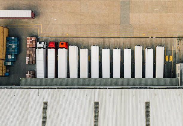 Overhead view of a loading dock with parked semi-trucks, storage, and a warehouse.
