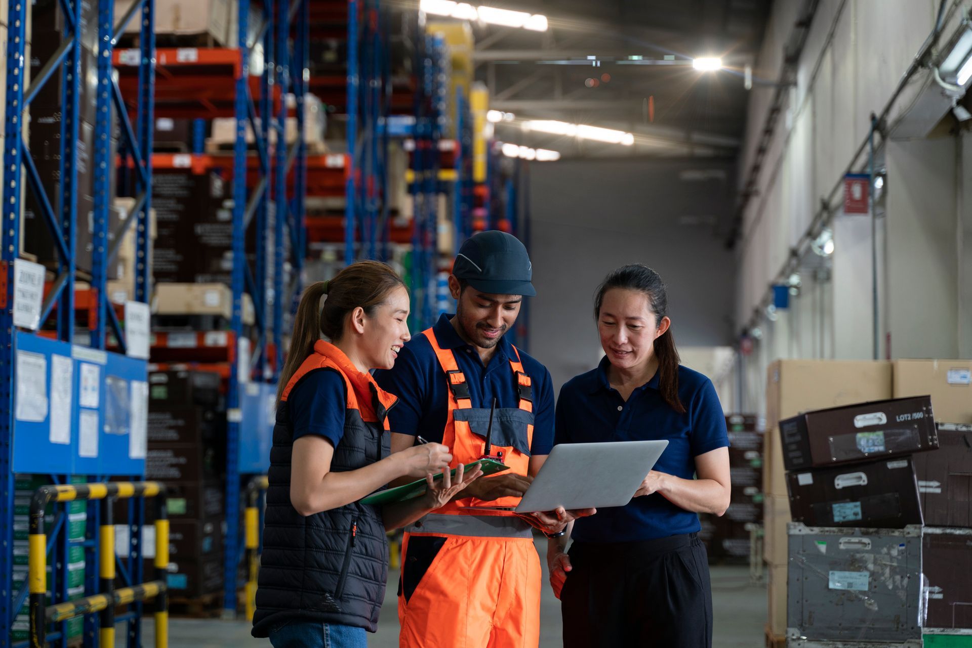 Warehouse workers reviewing inventory on laptop.