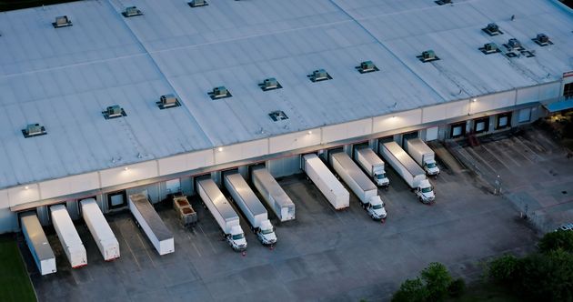 Warehouse with several semi-trucks docked at loading bays, preparing for loading and unloading.