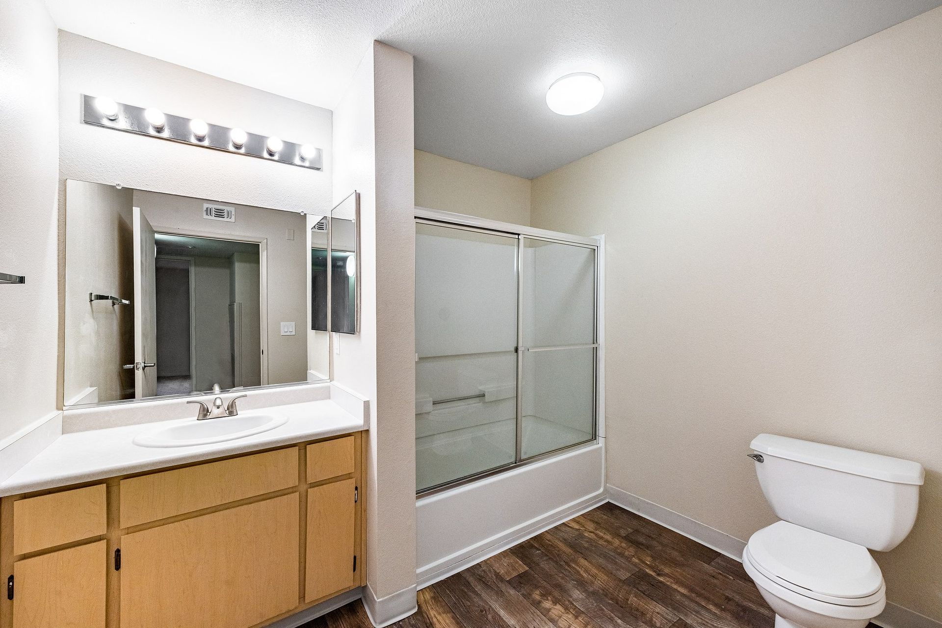 Bathroom in an apartment with vanity, mirror, and sliding-glass shower.