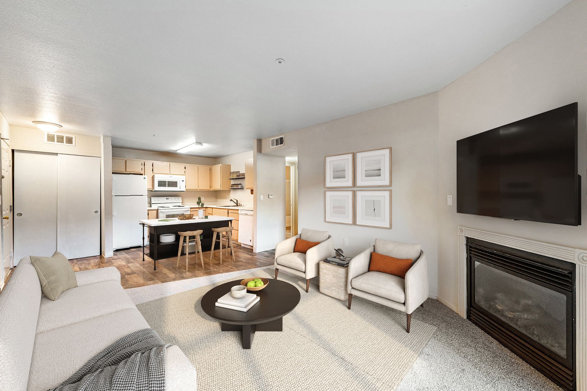 Open-concept living room with beige sofa, two armchairs, coffee table, fireplace, and wall-mounted TV.