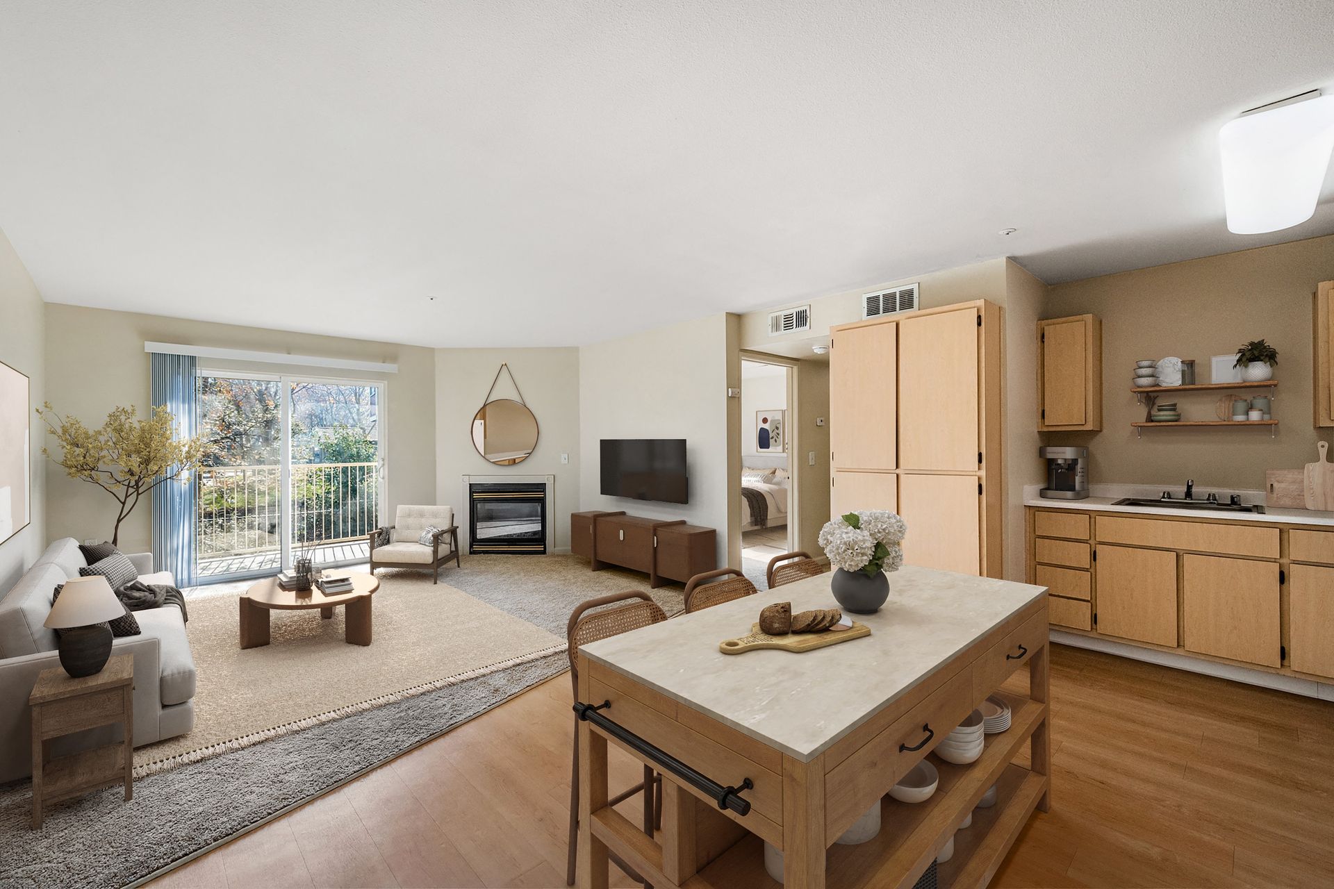 Open-concept living room and kitchen in an apartment with sofa, fireplace, TV, island, and balcony.