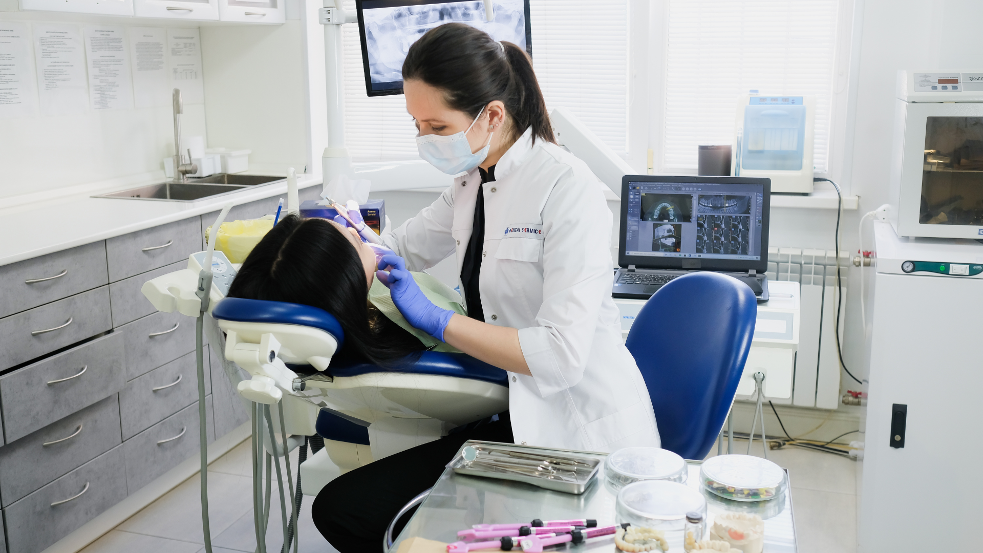 A female dentist is examining a patient 's teeth in a dental office.