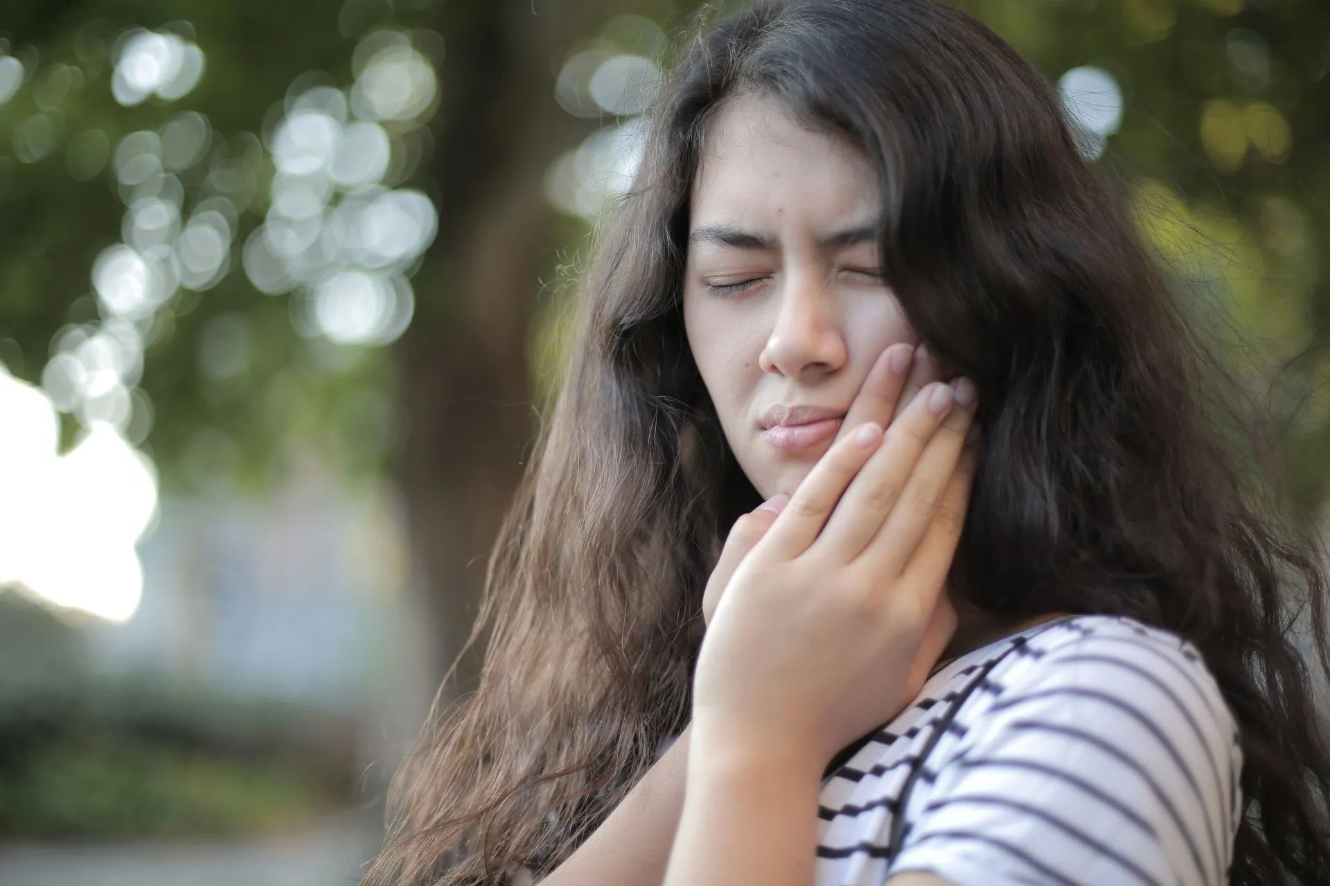 A young woman is holding her face in pain because of a toothache.