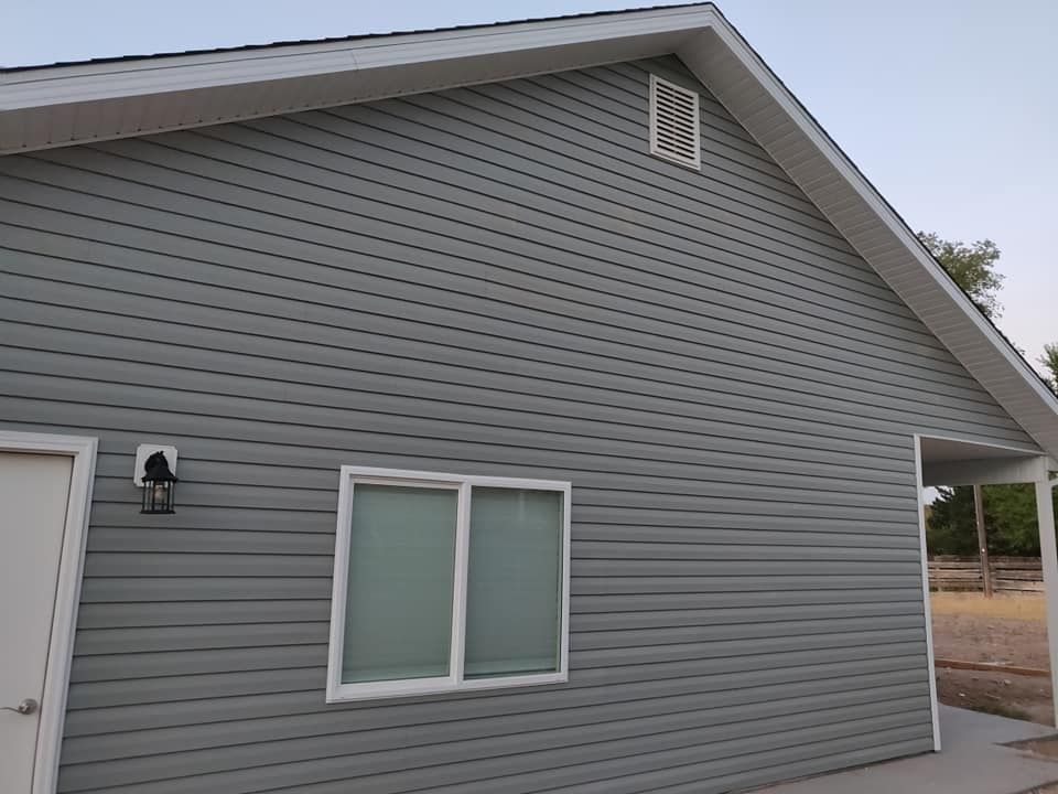 Gray-sided building with white trim, a window, and a vent.