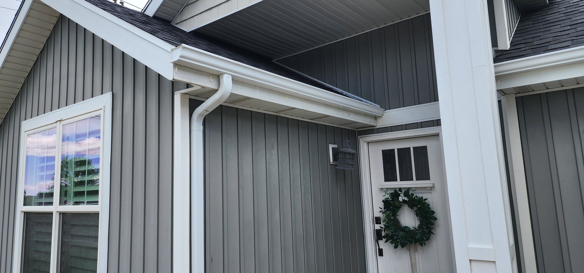 Gray house with white trim, gutters, and a wreath on the door.