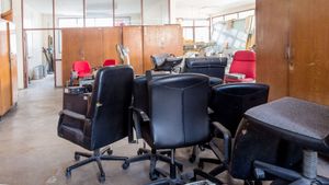 An office space filled with several black rolling office chairs and a few red chairs near wooden partition walls.