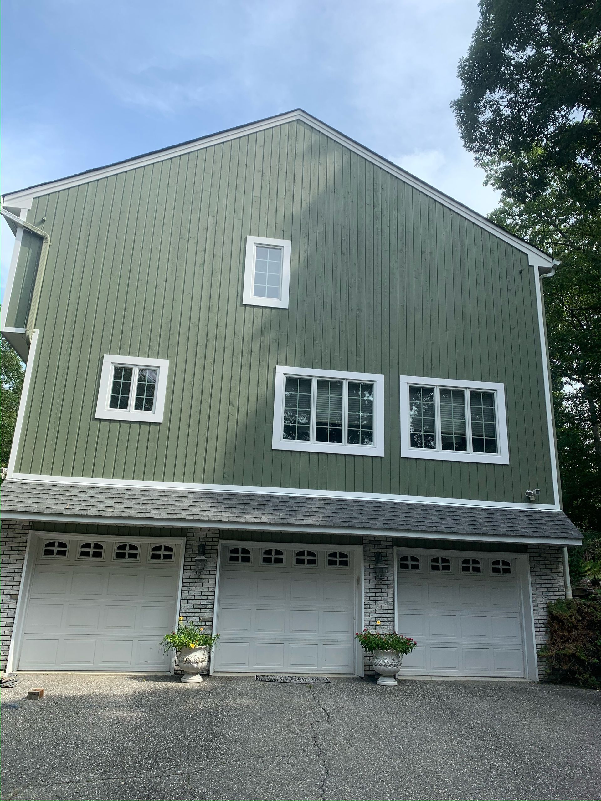 A large green house with three garage doors and three windows.