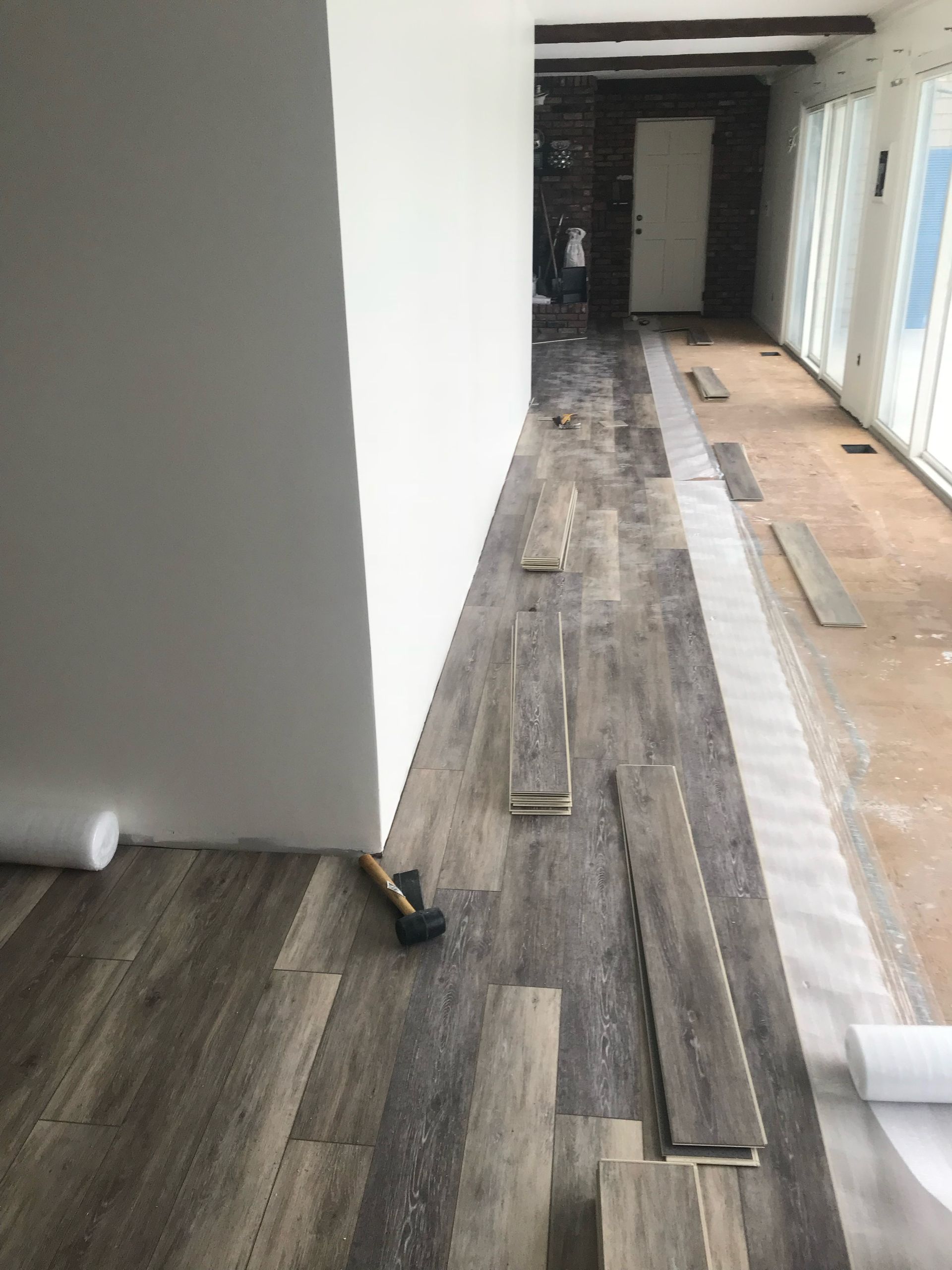 A hammer is sitting on a wooden floor in a room.