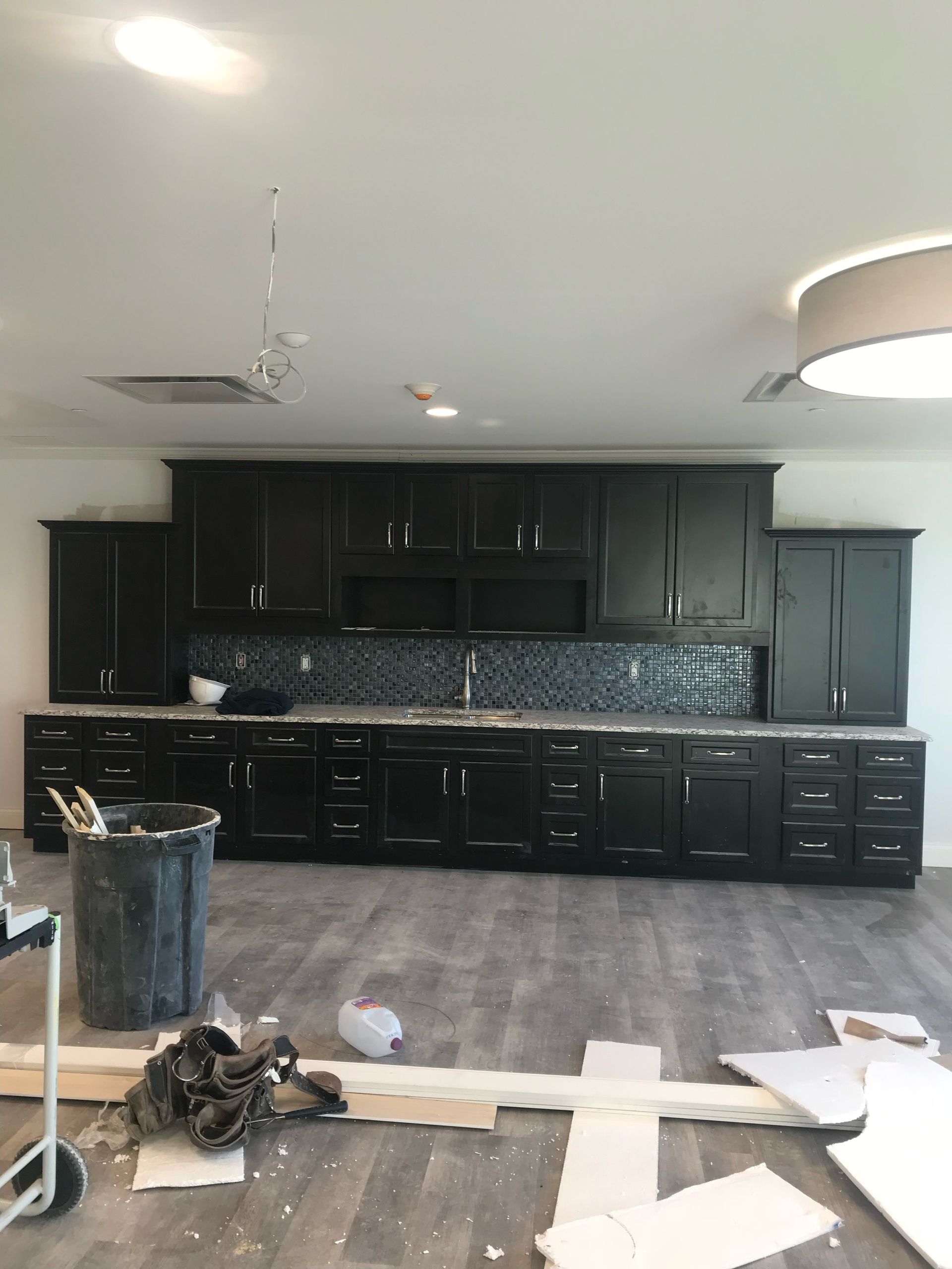 A kitchen is being remodeled with black cabinets and granite counter tops.