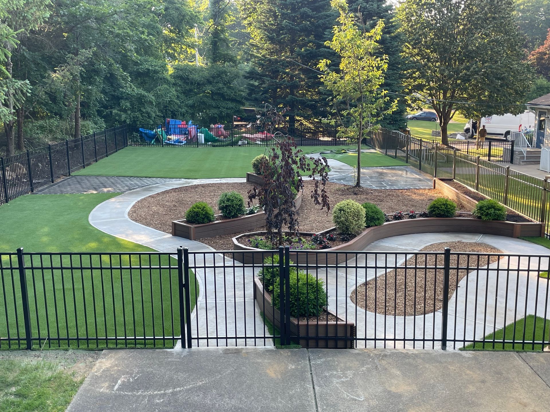 A fence surrounds a lush green yard with a playground in the background.