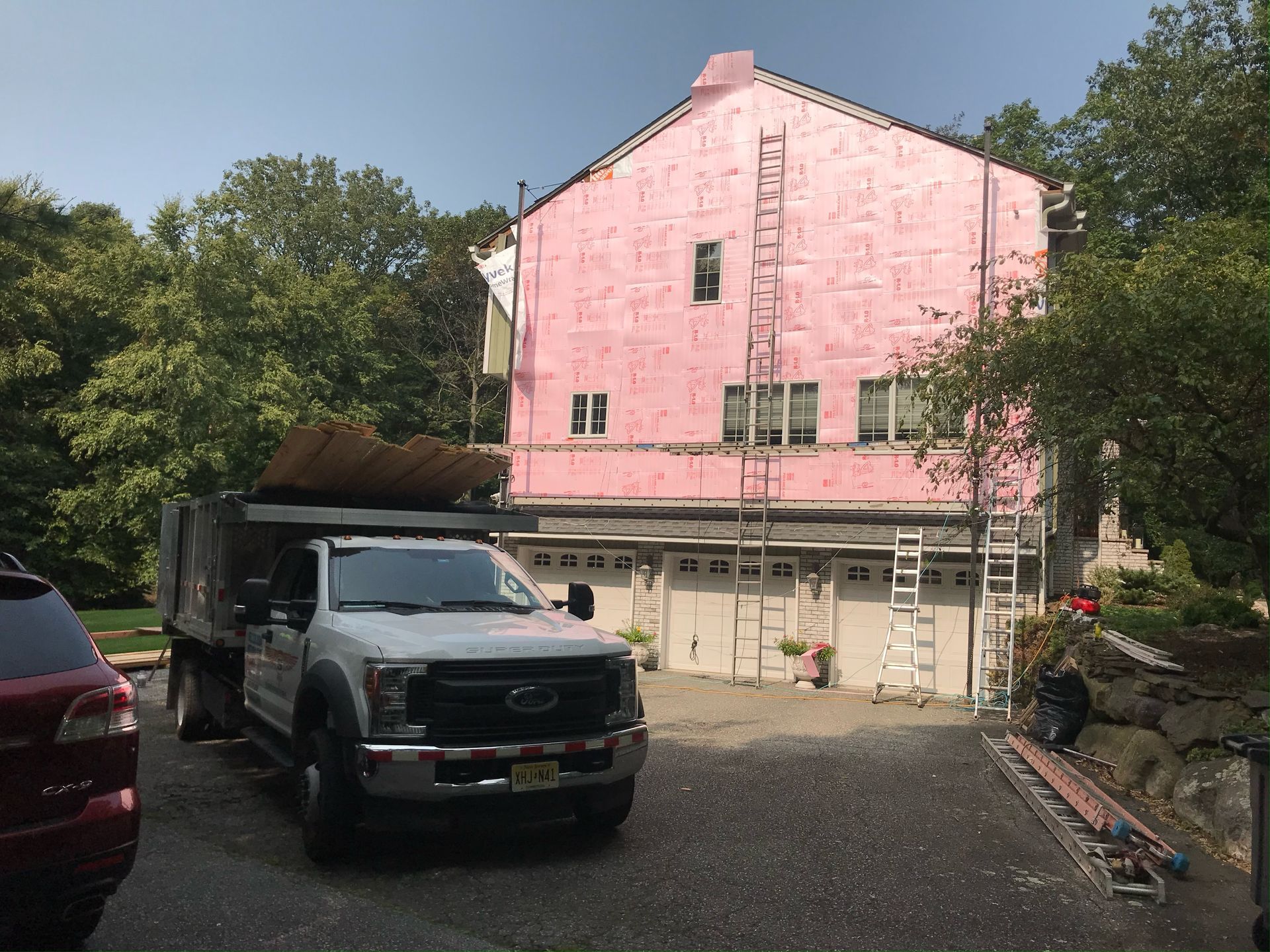 A white truck is parked in front of a pink house.
