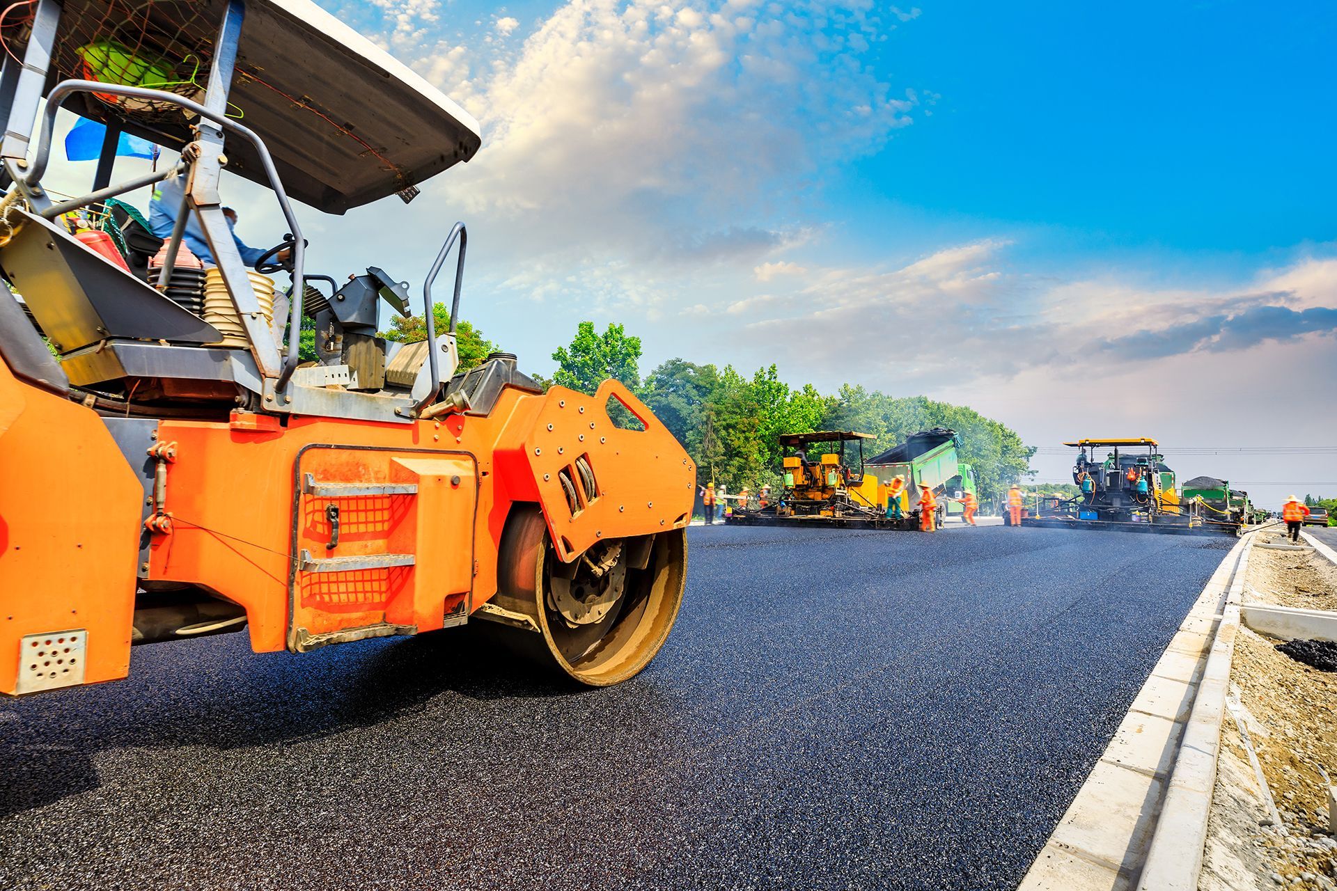 A group of construction vehicles are working on a road.