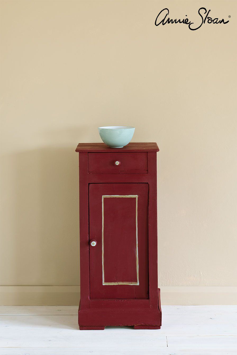 Ein kleiner roter Schrank mit einer Schüssel darauf.
