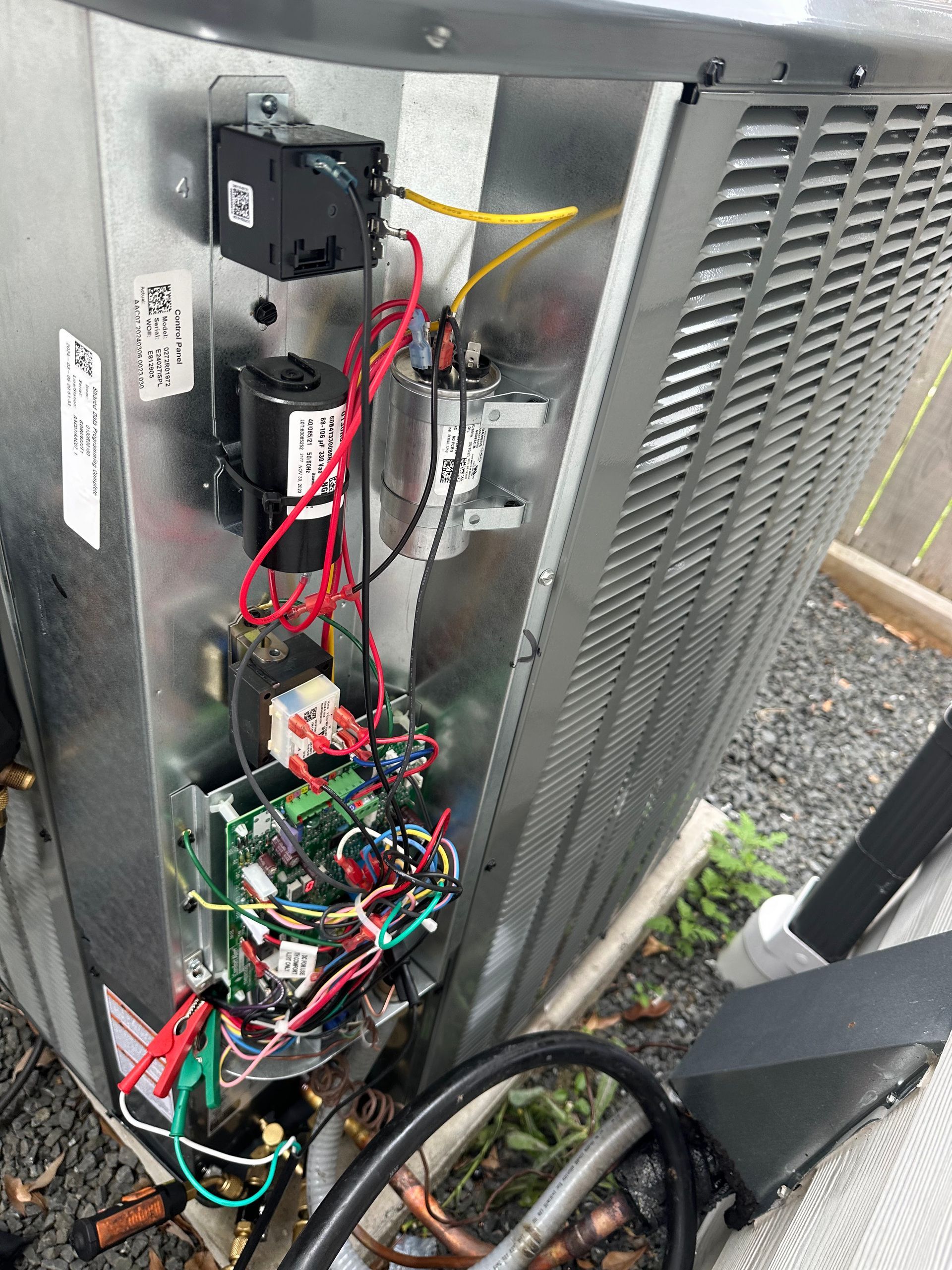 Open air conditioning unit with exposed wiring and circuit board. Metal and plastic components, various colored wires.