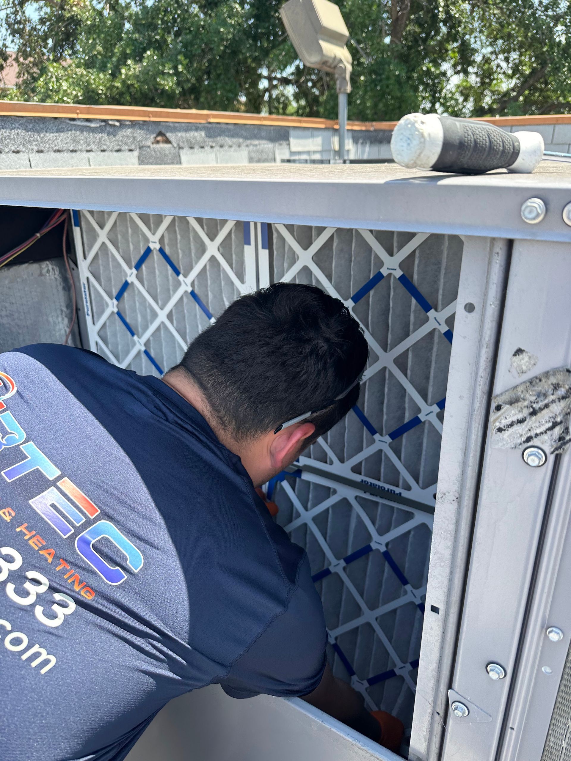 HVAC technician replacing an air filter on a rooftop unit.