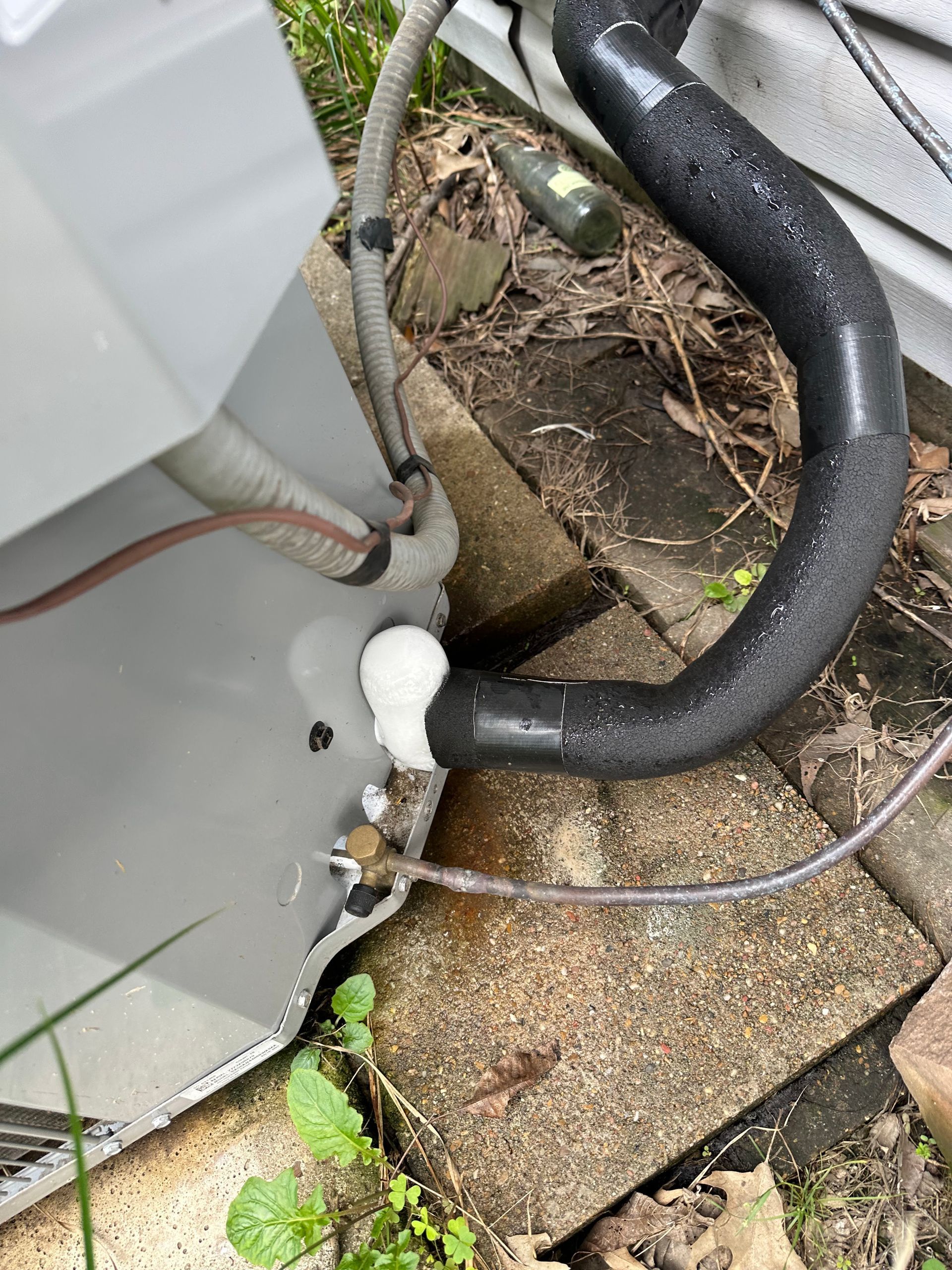 Outdoor air conditioning unit with frozen insulation, showing a white ice build-up.