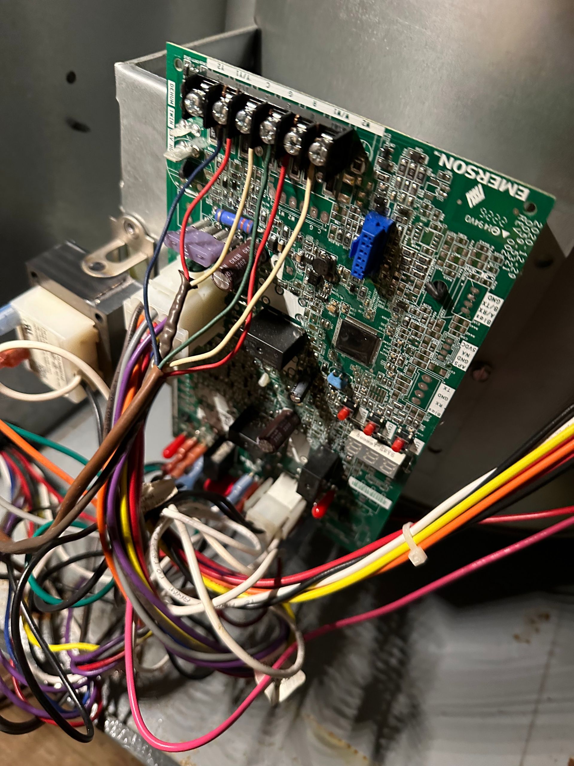 Circuit board with various colored wires attached.