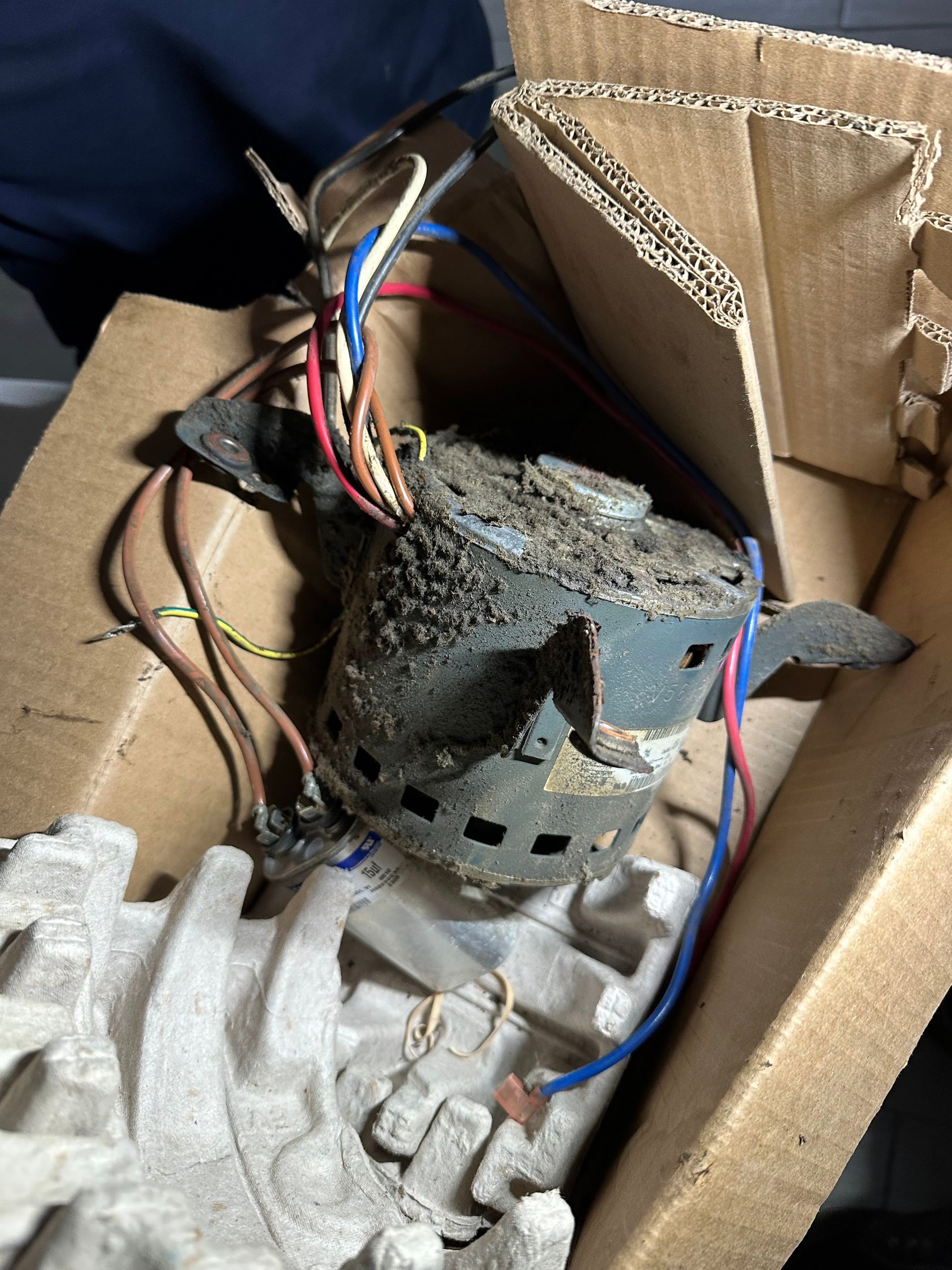 Damaged motor with exposed wires inside a cardboard box.