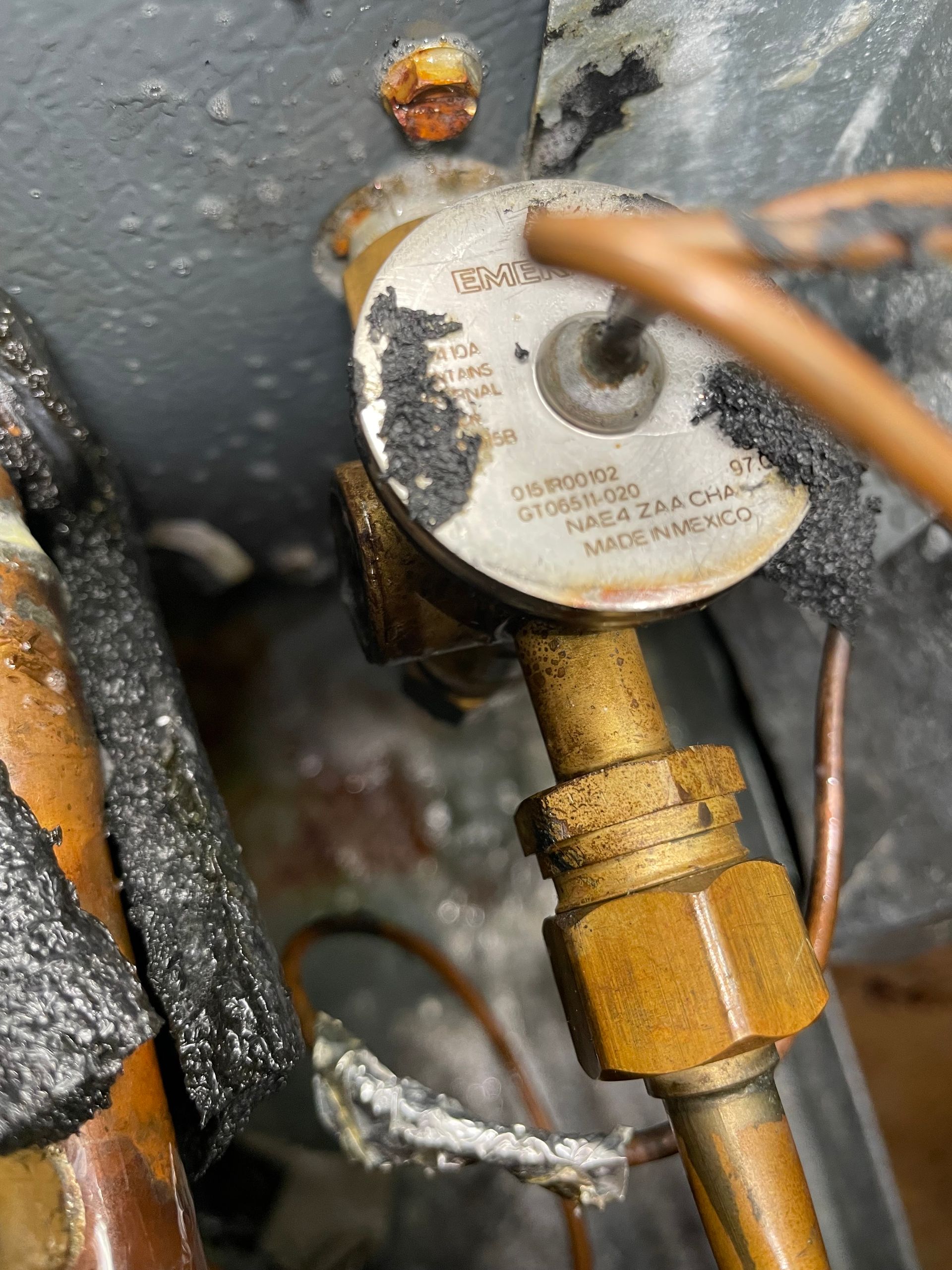 Close-up of a damaged HVAC component, likely a valve. Burnt insulation and metal.