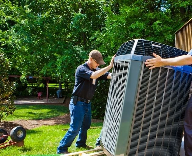 Two men installing an outdoor air conditioning unit in a yard.