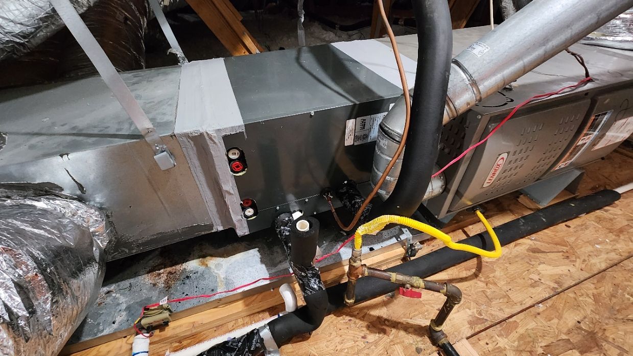 HVAC unit in an attic with ductwork, electrical wiring, and gas lines, all in a wood-framed space.