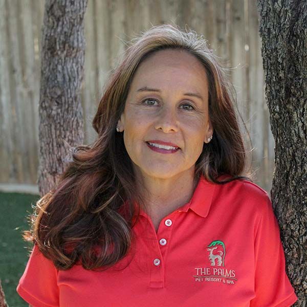 A woman in a red shirt is leaning against a tree.