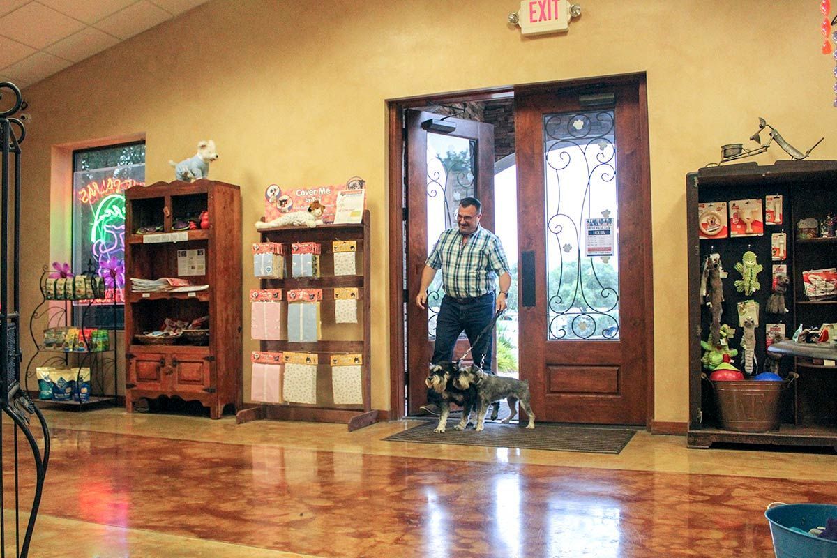 A man is walking a dog through a doorway in a store.