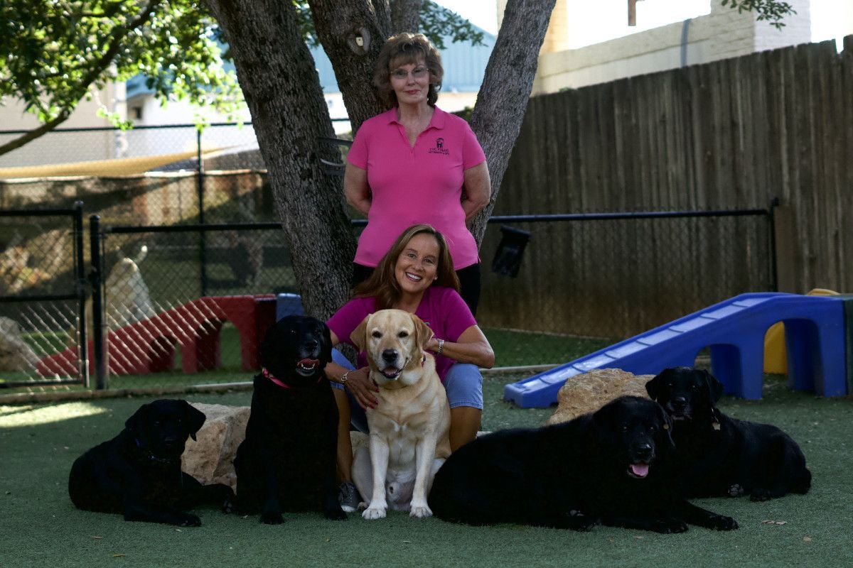 Two women are posing for a picture with their dogs