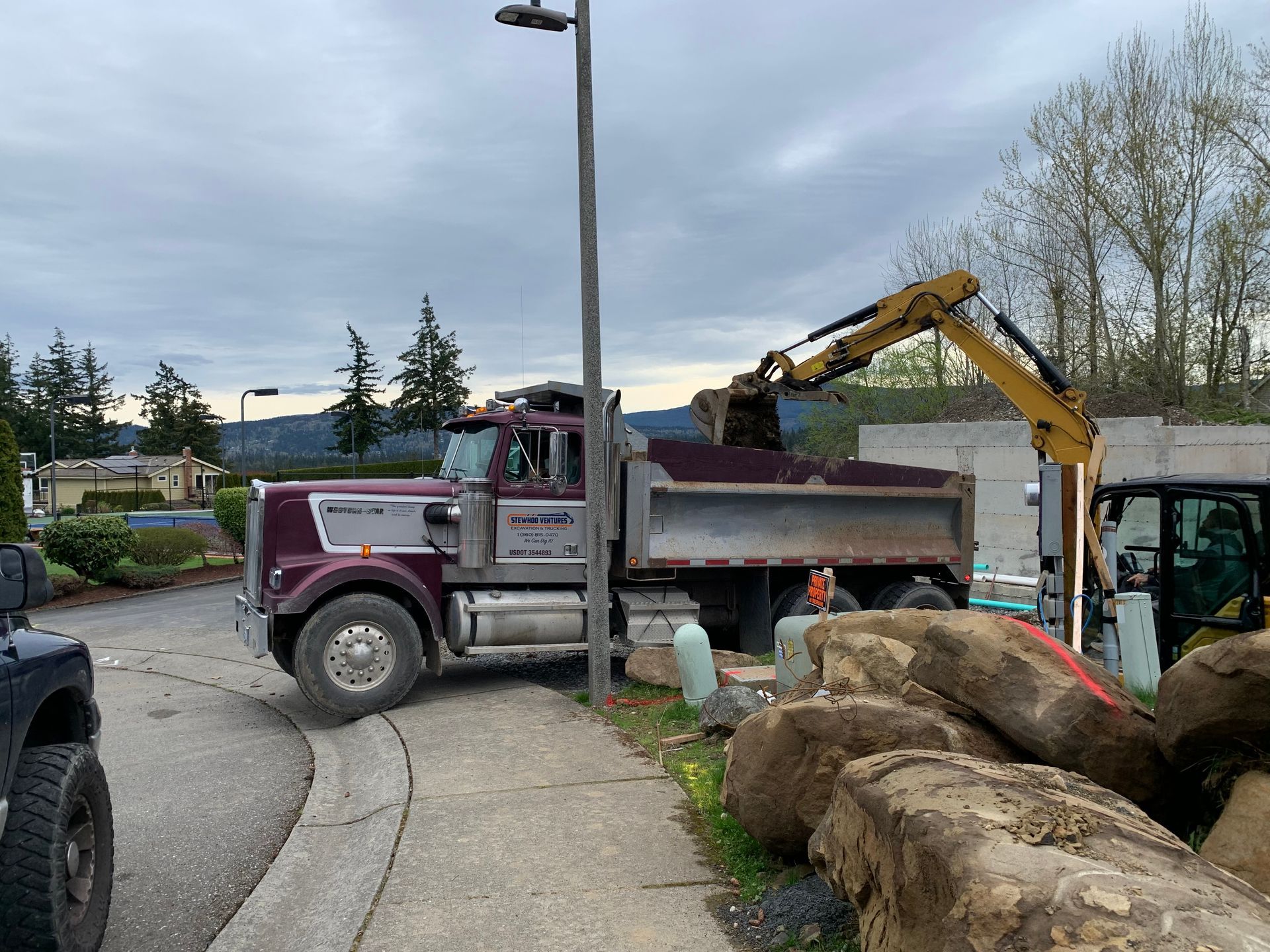 Green and black industrial rock crusher in a gravel pit with a person nearby.